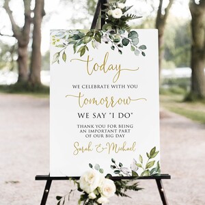 May include: A white sign with green foliage and gold lettering. The sign reads "today we celebrate with you tomorrow we say 'I do' thank you for being an important part of our big day Sarah & Michael"
