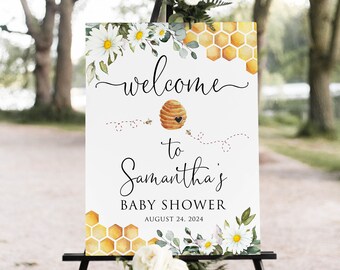 Op de afbeelding: Welkom op Samantha's babyshower bord met een bijenkorf en madeliefjes. Het bord staat op een zwarte ezel en heeft een witte achtergrond met een geel honingraatpatroon. De tekst luidt "Welkom op Samantha's babyshower 24 augustus 2024".