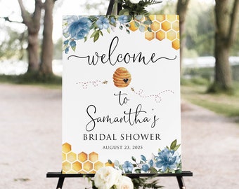 May include: Welcome to Samantha's Bridal Shower sign with a beehive and bees, blue flowers, and honeycomb pattern. The sign is on a black easel and the date is August 23, 2025.