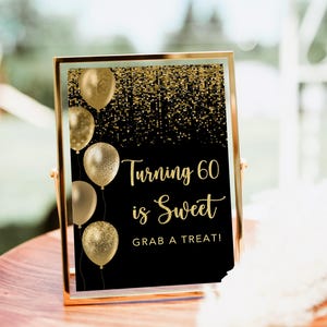 May include: A gold-framed sign with the text "Turning 60 is Sweet, Grab a Treat!" against a black background. Gold balloons and a gold glitter design are also featured. The sign is displayed on a wooden table.