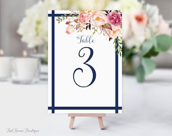 May include: White table number card with a navy blue border and floral design. The card says "Table 3" in a navy blue script font.