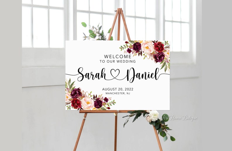 K&ouml;nnte beinhalten: Ein wei&szlig;es Hochzeitsschild mit burgunderroten und blushfarbenen floralen Akzenten. Das Schild lautet "Willkommen zu unserer Hochzeit Sarah Daniel 20. August 2022 Manchester, NJ".