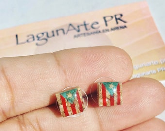 May include: A pair of small square earrings with the Puerto Rican flag embedded in the center. The earrings are made of resin and have a clear backing.
