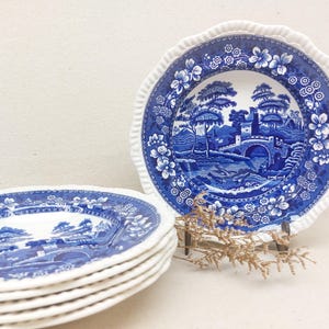 Könnte beinhalten: Set aus fünf blauen und weißen Keramiktellern mit einem Blumenmuster und einer Szene mit einer Brücke über einem Fluss. Die Teller haben einen gewellten Rand.