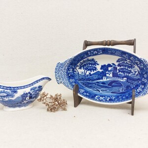 Peut inclure: Un saucier et un plat de service ovales en porcelaine bleu et blanc avec un motif floral bleu et blanc. Le plat est sur un support en bois.