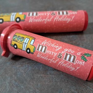 May include: Two red and white tubes with a yellow school bus design and the text "Wishing you a merry & most Wonderful Holiday!" printed on them.