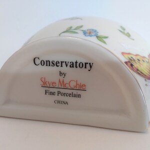 May include: A white porcelain butter dish with a gold trim and a butterfly design. The dish is labelled "Conservatory by Skye McGhie Fine Porcelain CHINA".