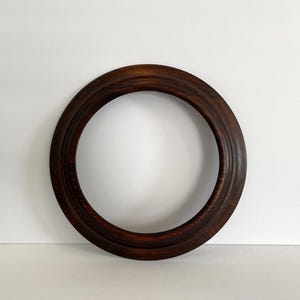 May include: A dark brown wooden picture frame with a rounded edge and a smooth finish.