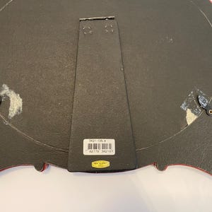 May include: Black oval picture frame with a red and gold ornate design. The back of the frame has a label with the text "3421-08-W" and a barcode.