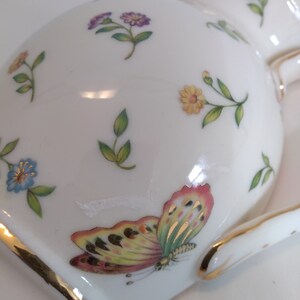 May include: White porcelain jug with a gold trim and a floral pattern. The jug features a butterfly with yellow, green, and pink wings.