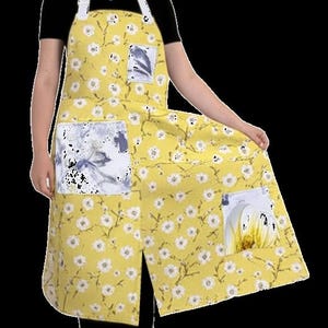 May include: Yellow floral apron with white straps and two large pockets. The apron features a pattern of small white flowers and green stems on a yellow background. The pockets have watercolor-style floral designs.