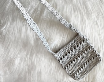 May include: A small, crocheted, grey bag with a long strap. The bag has a simple, open weave pattern.
