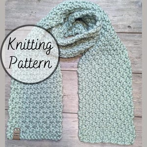 May include: A light green knitted scarf with a textured stitch pattern. The scarf is folded in half and laid out on a wooden surface. The text "Knitting Pattern" is written in black on a white circle.