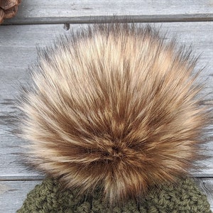 May include: A brown and blonde faux fur pom pom for a hat. The pom pom is fluffy and soft.