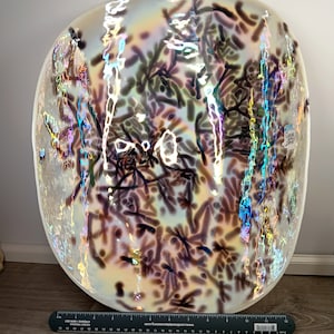 Puede incluir: Un cuenco grande de vidrio iridiscente de forma ovalada con un patrón de remolino de marrón y blanco. El cuenco tiene un acabado nacarado y es perfecto para servir aperitivos o fruta.