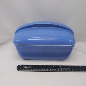 May include: A light blue ceramic casserole dish with a lid. The lid has a curved handle.