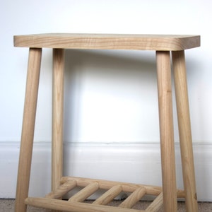 May include: A light wood side table with a shelf. The table has a simple design with four legs and a rectangular top.