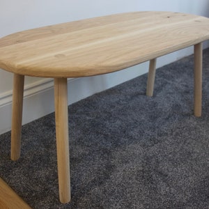 Handmade rounded end solid oak coffee table with four straight turned legs fixed with visible contrasting wedge tenon joints.