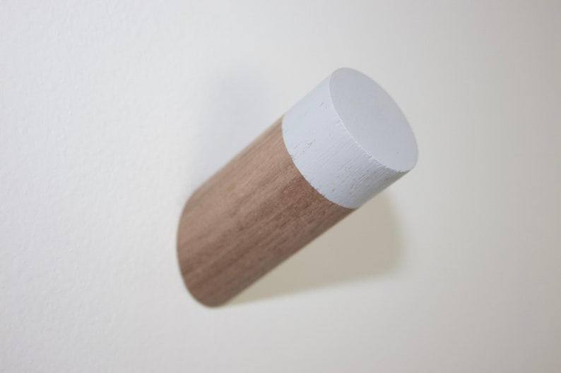 May include: A wooden wall hook with a white painted top. The hook is made of natural wood and has a simple, modern design.