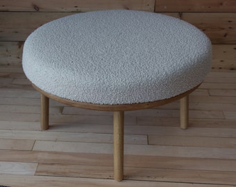 Round solid oak footstool with four turned legs with a padded cushion and upholstered in a chunky boucle fabric