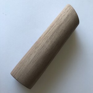 May include: A light brown wooden dowel rod with a slightly rounded end.