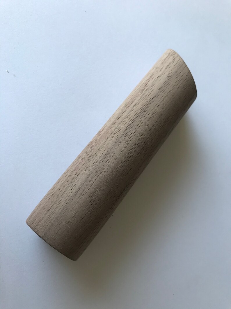 May include: A light brown wooden dowel rod with a slightly rounded end.