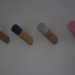 May include: Four wooden wall hooks with different colored tops. The hooks are white, navy blue, light gray, and pink.