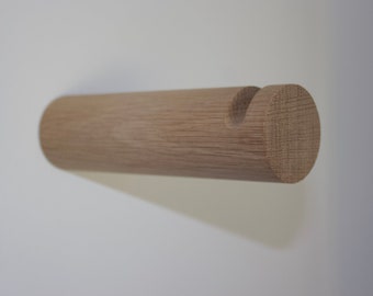 May include: A wooden wall hook with a rounded shape and a notch for hanging items. The hook is made of light brown wood and has a natural finish.