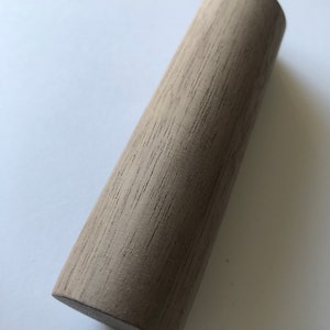 May include: A light brown wooden cylinder with a smooth, slightly textured surface.