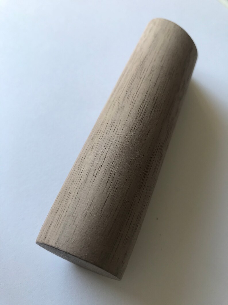 May include: A light brown wooden cylinder with a smooth, slightly textured surface.