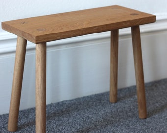 Handmade solid oak milking stool with four turned straight legs secured into position with contrasting wedged tenons finished in danish oil