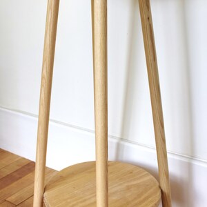 May include: A wooden side table with a round top and three legs. The table has a lower shelf.