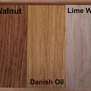 May include: Five rectangular wood samples arranged side-by-side, each displaying a different finish. The labels are Dark Oak, Walnut, Danish Oil, Lime Wax, and Beeswax. Each piece shows distinct wood grain patterns and varying shades of brown.
