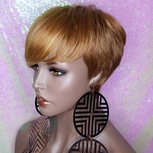May include: A short, blonde wig with side-swept bangs. The wig is styled in a pixie cut and is worn by a mannequin with large, geometric earrings.