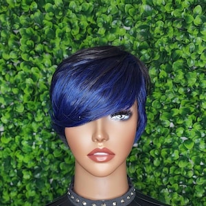 Puede incluir: Una peluca corta azul y negra con flequillo. La peluca está peinada con un corte pixie y raya lateral. La peluca está en una cabeza de maniquí.
