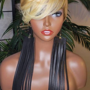 May include: A mannequin with short, blonde hair wearing long, black leather fringe earrings.