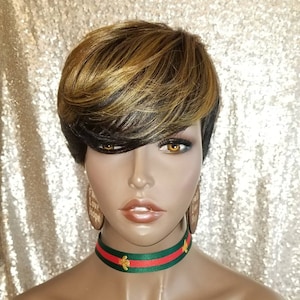May include: A short, layered wig with blonde and black highlights. The wig is styled with a side part and bangs. The model is wearing a green and red choker with a bee design.