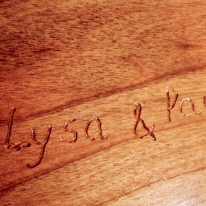May include: Close-up of a wooden surface with the names "Alyssa & Paul" carved into it.