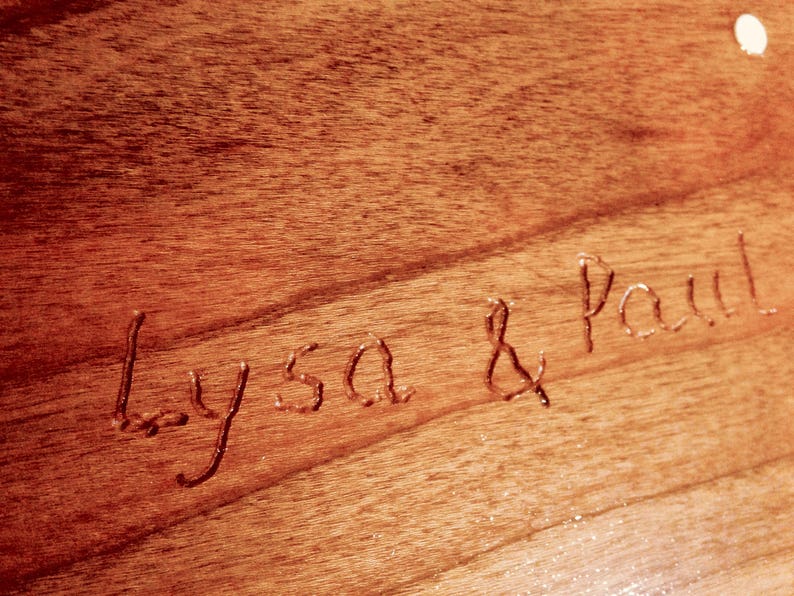 May include: Close-up of a wooden surface with the names "Alyssa & Paul" carved into it.