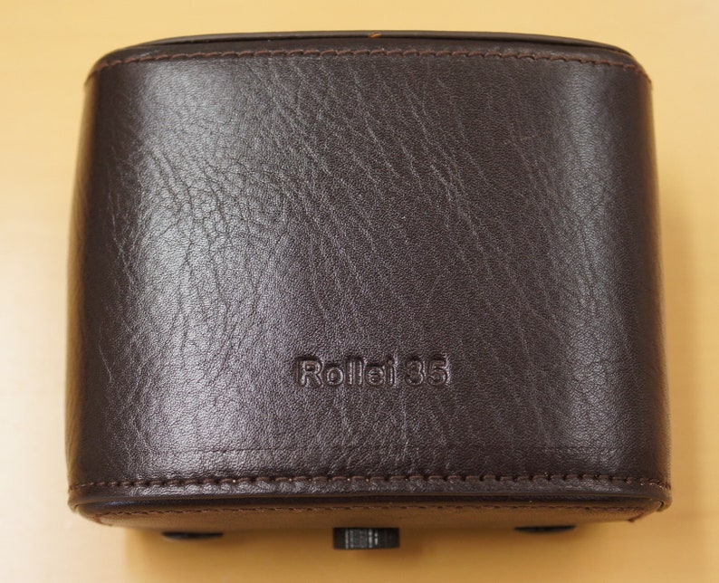 May include: A brown leather camera case with the text "Rollei 35" embossed on the front.