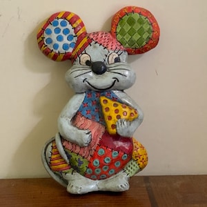 May include: A colorful patchwork mouse figurine with a smiling face and holding a yellow and red patchwork heart. The mouse is made of ceramic and has a distressed paint finish.