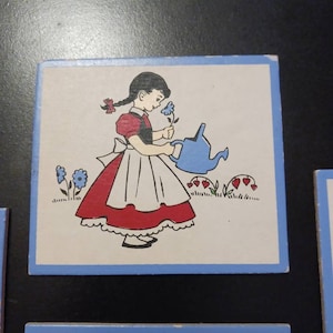 May include: A vintage tile featuring a girl in a red and white dress watering a flower with a blue watering can. The tile has a blue border and a white background.