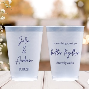 May include: Two clear plastic cups with blue text. The first cup says "Jolie & Andrew 9.18.21". The second cup says "some things just go better together #newlyweds".