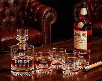 May include: A clear glass decanter and four matching tumblers, each with a custom design, sit on a dark wooden surface. A bottle of red wine and a cigar are also present, suggesting a bar or lounge setting.