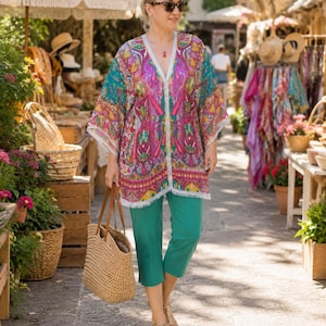 Turquoise pink paisley silk kaftan top worn with turquoise capri pants and straw tote at a sunny resort market.
