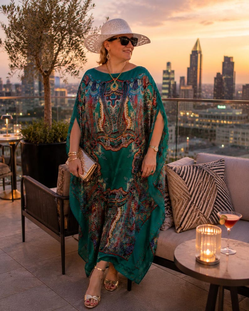 Designer inspired aquamarine silk paisley kaftan in a rooftop restaurant setting, flowing maxi beach cover up and plus size vacation outfit.
