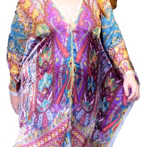 May include: A woman wearing a colorful, patterned, long-sleeved dress with a V-neckline. The dress has a paisley design with shades of blue, purple, red, yellow, and white.