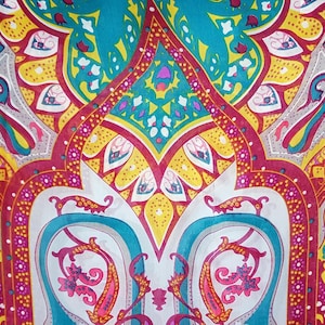May include: A fabric textile featuring a vibrant, symmetrical paisley pattern in shades of teal, magenta, bright yellow, and white. The design consists of intricate teardrop shapes, floral motifs, and geometric borders arranged in a repeating layout.