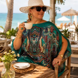 Plus size aquamarine silk kaftan with paisley print styled on a luxury resort terrace, elegant wedding guest dress and beach cover up for tropical holidays.