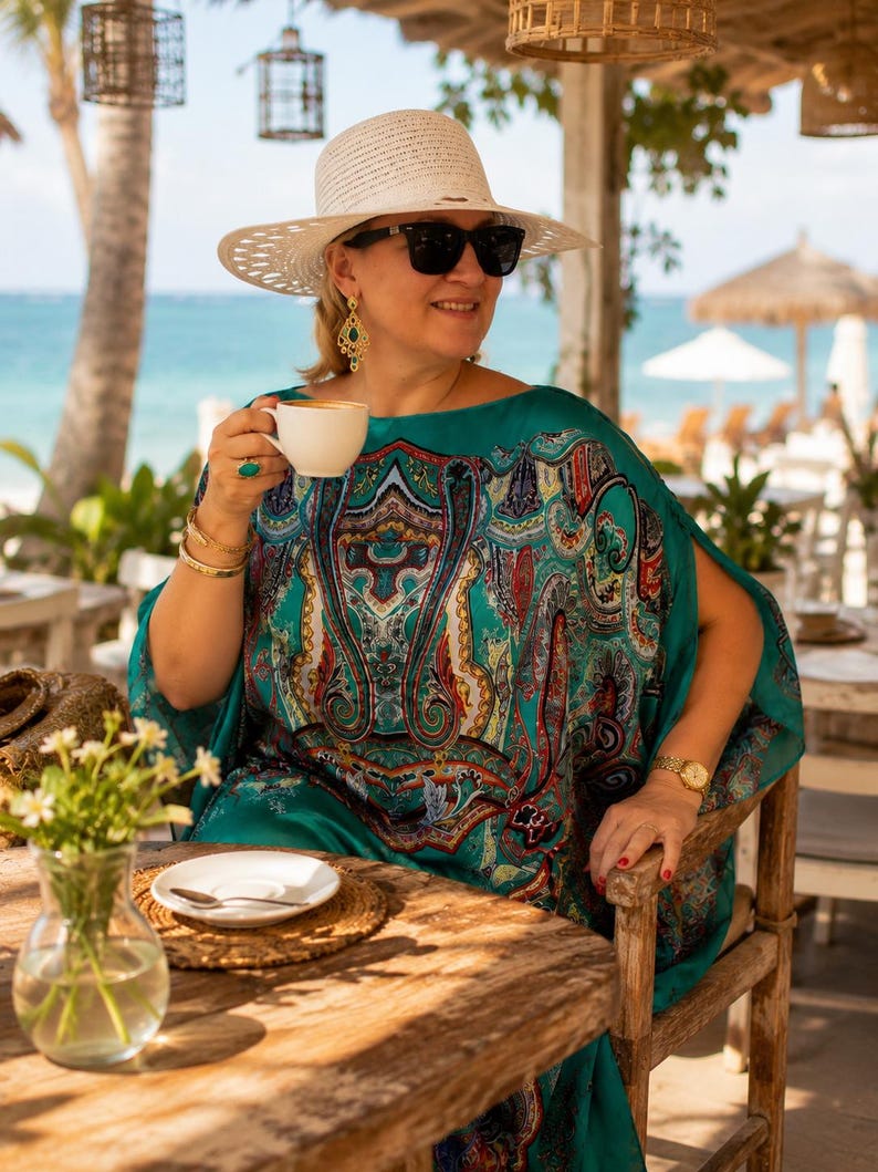 Plus size aquamarine silk kaftan with paisley print styled on a luxury resort terrace, elegant wedding guest dress and beach cover up for tropical holidays.